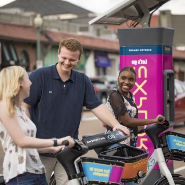 一对年轻男女在一个小购物中心的共享单车站租了一辆自行车.