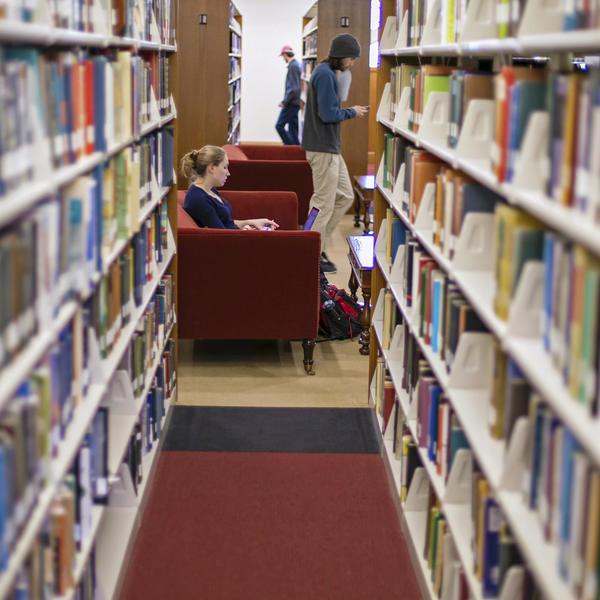 一个学生在图书馆的书堆里学习