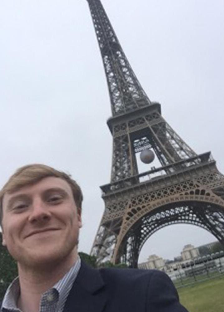 a male student in front of the eiffel tower